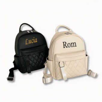 2 rugzakken van imitatieleer. de ene wit, de andere zwart, gepersonaliseerd met de namen Lucia en Rom op een lichtgrijze achtergrond