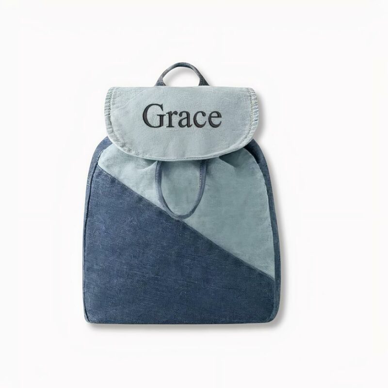 Blauwe denim kinderrugzak gepersonaliseerd met de naam van Grace op een lichtgrijze achtergrond