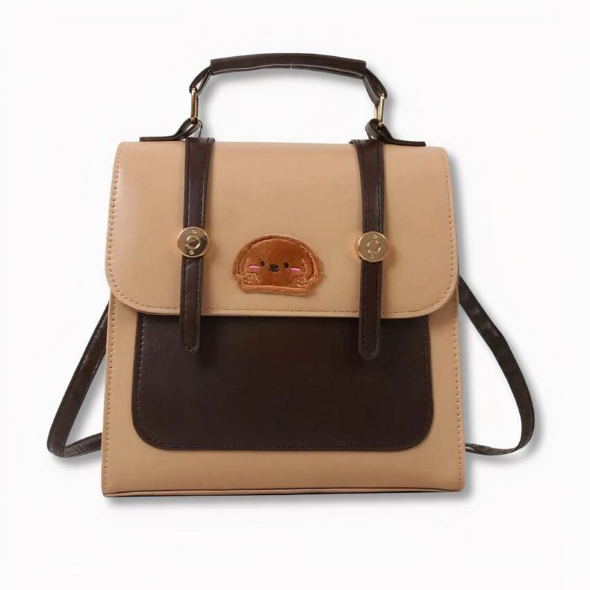 Bruine en beige schooltas met hondengezichtbadge op de voorkant, op een lichtgrijze achtergrond