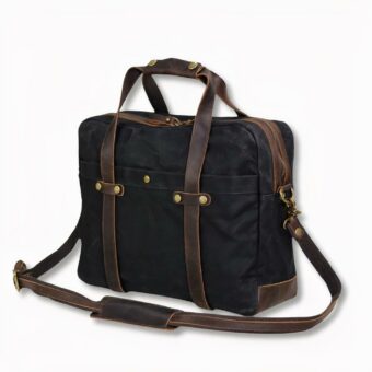 Herensatchel van zwart gewaxt canvas met schouderriem, op een lichtgrijze achtergrond